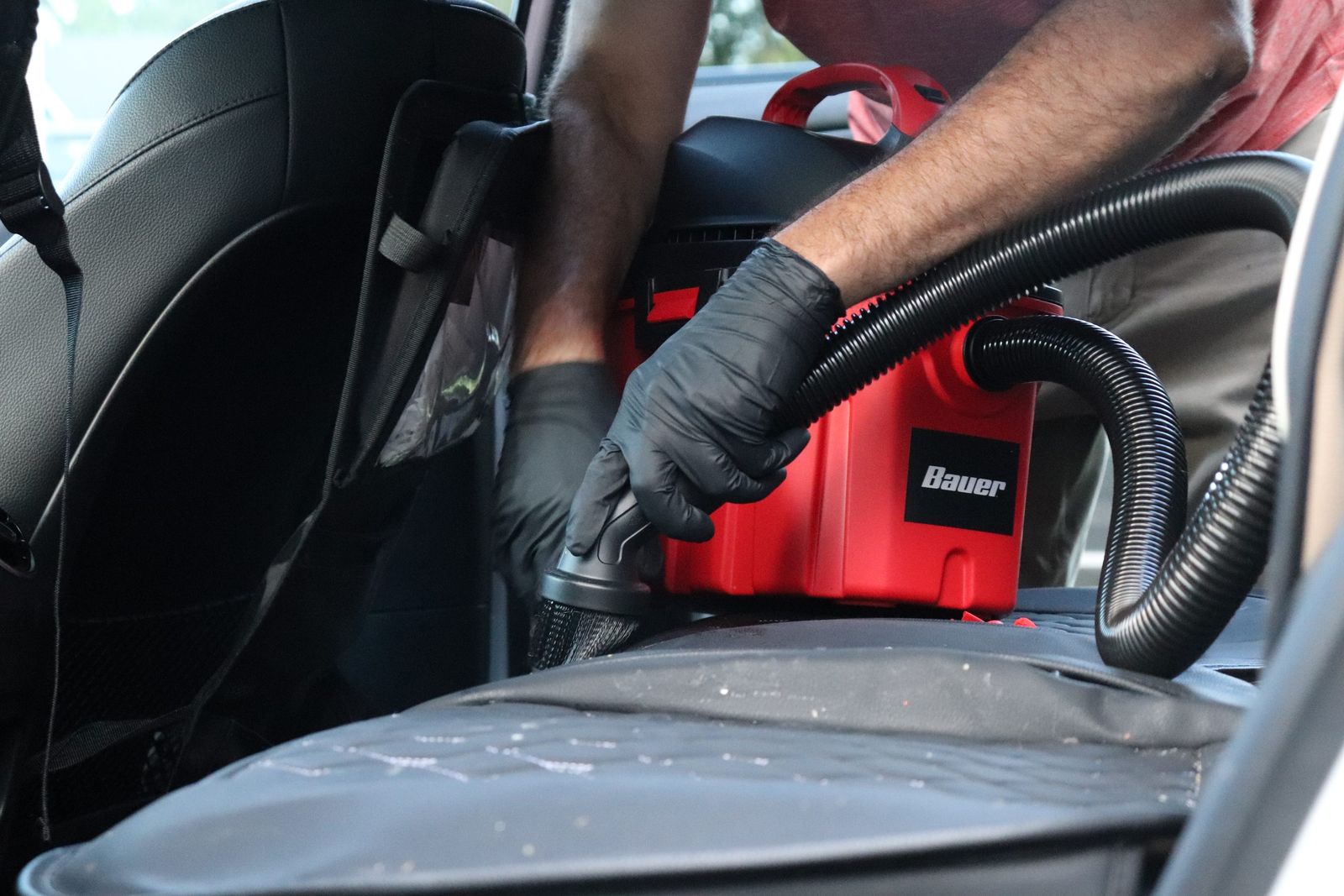 Vacuuming a leather seat with a detail brush